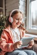 Smiling Young Girl Enjoying Music on Headphones While Holding a Tablet by the Window