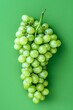 Fresh Green Grapes Cluster With Leaves on a Solid Green Background