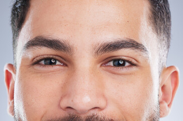 Wall Mural - Happy man, portrait and eyes with natural skin for grooming, eyebrows or masculine beauty on a gray studio background. Closeup of handsome male person or young model staring with iris, gaze or pupil