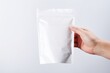 © OGGYA - hand is holding white pouch snack packaging for mockup