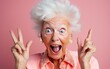 Funny elderly woman with silly expression makes gestures, happily and feels proud of her success, smiles gladfully