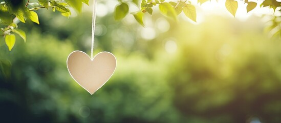 Poster - A tranquil paper sheet hangs from a thread adorned with a heart shaped clothespin against a backdrop of lush greenery A copy space image
