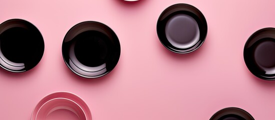 Aufkleber - Top view of a pink background showcasing a set of black ceramic plates and gravy boats perfect for copy space images
