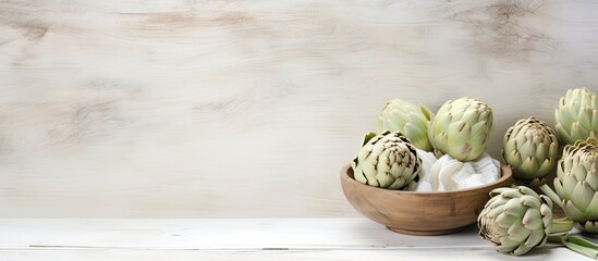 Leinwandbilder - The white wooden table is adorned with a bowl filled with powder and fresh artichokes creating an appealing flat lay composition Ample space is available for text