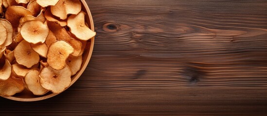 Wall Mural - An organic natural food consisting of dried apple chips is beautifully presented in a close up top view on a brown wooden table creating a visually appealing copy space image