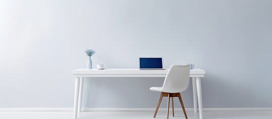 Poster - A white table with a chair and a laptop creating a minimalist setting with copy space image