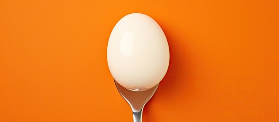 Poster - A half boiled egg on an orange background with a copy space image balanced on a fork