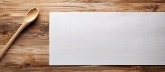 Poster - Top view of a wooden table with a close up shot of a cooking wooden spatula and lined paper creating a copy space image