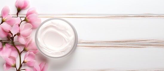 Poster - On a white wooden table there is a cosmetic cream accompanied by beautiful pink flower petals giving a delightful copy space image