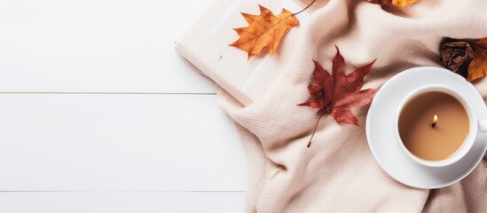 Aufkleber - A cozy autumn home composition with dried leaves a cup of coffee a book a scarf and flowers on a white background The image showcases the essence of fall with a flat lay top view and copy space