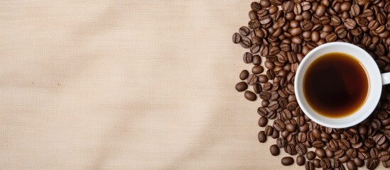Aufkleber - A top view copy space image of a coffee cup resting on a linen cloth background surrounded by coffee beans