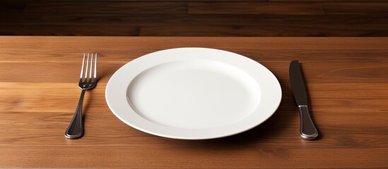 Poster - A concept image of white plate fork and knife placed on a wooden table along with cutlery and silverware. Creative banner. Copyspace image