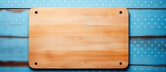 Wall Mural - A blue wooden background in a cafe with a cutting board frame placed on a tablecloth filled with polka dots leaving space for a copy image. Creative banner. Copyspace image