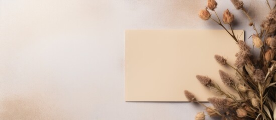 Poster - Top view of a beige background with a mockup of an invitation or greeting card It features an envelope beautifully decorated with dry plants leaving ample copy space