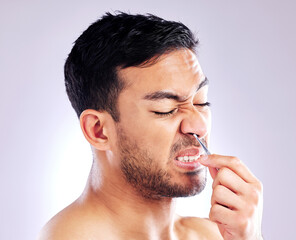 Canvas Print - Tweezers, man and remove nose hair, grooming and hygiene on white studio background. Person, model and guy with treatment, beauty or pain with beard, expression or facial care with luxury or wellness