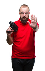 Poster - Young caucasian hipster man filmming using retro video camera over isolated background with open hand doing stop sign with serious and confident expression, defense gesture