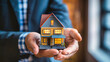 © Anoo - A man holds a small model house in his hands, symbolizing real estate sales, mortgage opportunities, and the dream of home ownership