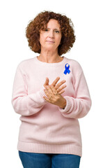 Sticker - Middle ager senior woman wearing changeable blue color ribbon awareness over isolated background Suffering pain on hands and fingers, arthritis inflammation