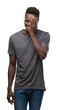 © Krakenimages.com - Young african american man wearing grey t-shirt covering one eye with hand with confident smile on face and surprise emotion.