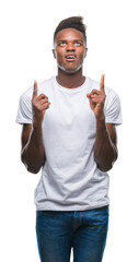 Sticker - Young african american man over isolated background amazed and surprised looking up and pointing with fingers and raised arms.