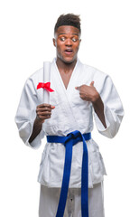 Sticker - Young african american man over isolated background wearing kimono holding degree with surprise face pointing finger to himself