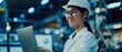 © Антон Сальников - In a white hard hat, a smiling Asian woman stands with a laptop computer at an electronic manufacturing plant. Focusing on a PC screen, the employee is happy and confident.