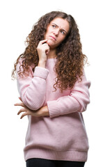 Wall Mural - Beautiful brunette curly hair young girl wearing pink winter sweater over isolated background with hand on chin thinking about question, pensive expression. Smiling with thoughtful face
