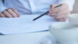 © peopleimages.com - Hand, medical paperwork and pen at desk for information, report or history with planning for wellness. Person, documents and writing with checklist, decision and legal contract for health in hospital
