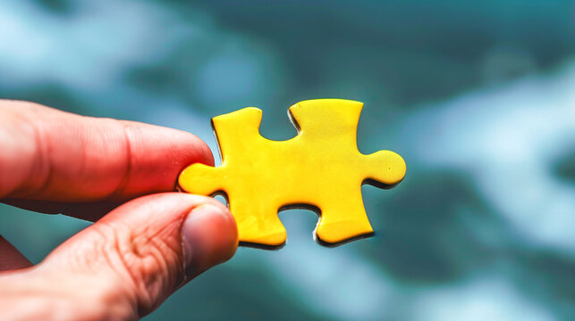 Hand Holding a Yellow Puzzle Piece with Blurry Background. the text can be placed on puzzle