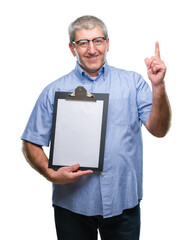 Wall Mural - Handsome senior inspector man holding clipboard over isolated background surprised with an idea or question pointing finger with happy face, number one