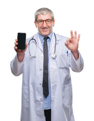 Canvas Print - Handsome senior doctor man showing screen of smarpthone over isolated background doing ok sign with fingers, excellent symbol