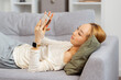 Young Woman Relaxing On Sofa With Smartphone, Enjoying Leisure Time At Home, Comfort And Technology Concept