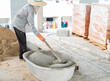 Worker manually mix cement powder , sand in basin.