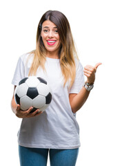 Sticker - Young beautiful woman holding soccer ball over isolated background pointing and showing with thumb up to the side with happy face smiling