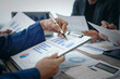 © Phushutter - A professional business team meeting in formal suits, working at desks with financial papers, calculators, and laptops. Close-up of hands. Discussion on revenue, brand, sales, agenda, capital
