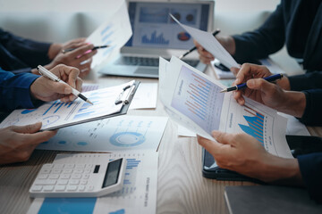 A professional business team meeting in formal suits, working at desks with financial papers, calculators, and laptops. Close-up of hands. Discussion on revenue, brand, sales, agenda, capital