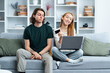 Young Couple Shopping Online, Woman Excited Holding Credit Card, Man Disinterested, Comfortable Home Setting