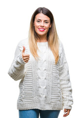 Poster - Young beautiful woman casual white sweater over isolated background doing happy thumbs up gesture with hand. Approving expression looking at the camera with showing success.