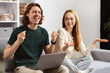 Couple Celebrating Online Success, Smiling Man And Woman On Couch With Laptop, Cheerful Victory Gesture