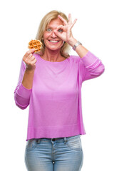 Poster - Middle age blonde woman eating sweet waffle over isolated background with happy face smiling doing ok sign with hand on eye looking through fingers