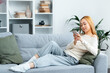 Young Woman Relaxing On Sofa With Smartphone, Casual Home Lifestyle, Comfortable Living, Modern Interior, Technology Use At Home