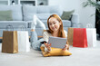 Young Woman Enjoying Online Shopping At Home, Smiling Asian Lady With Digital Tablet And Credit Card, Surrounded By Shopping Bags On Living Room Floor