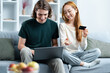 Couple Shopping Online On Couch With Laptop And Credit Card, Smiling Young Man And Woman Enjoying E-Commerce