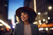 © CogniLens - Portrait of a grinning afro-american woman in her 20s donning a classic fedora isolated in background of bright city lights