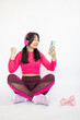 Relaxed athletic Asian woman browsing her phone after a workout session, surrounded by fitness equipment, do winner gesture.