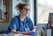 © Bambalino Studio - A doctor woman in a blue scrubs is sitting at a desk with a laptop. She is wearing a stethoscope around her neck