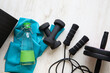 Various home workout tools at home floor. Exercise mat, jump rope, rubber band, dumbbells, water bottle.