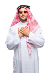 Wall Mural - Young handsome man wearing keffiyeh over isolated background smiling with hands on chest with closed eyes and grateful gesture on face. Health concept.