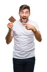 Canvas Print - Young handsome man eating chocolate bar over isolated background very happy pointing with hand and finger