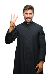Wall Mural - Young catholic christian priest man over isolated background showing and pointing up with fingers number three while smiling confident and happy.